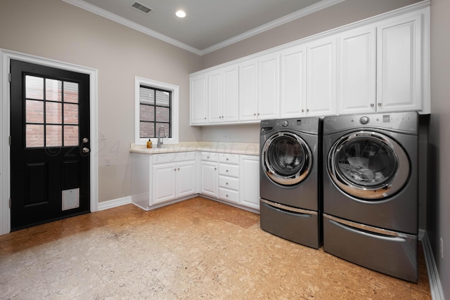 clothes washing area with washer and dryer, cabinets, ornamental molding, and sink