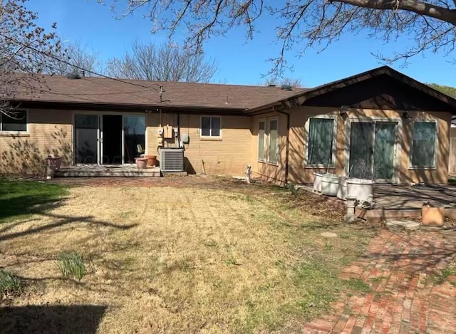 rear view of property featuring brick siding, a yard, and central air condition unit