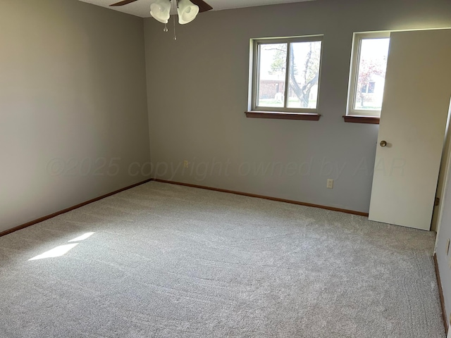 carpeted spare room featuring ceiling fan and baseboards