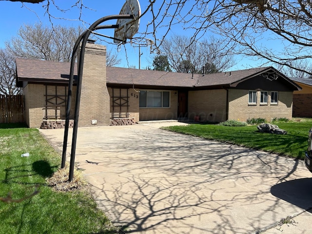 rear view of property featuring a lawn, a shingled roof, a chimney, and brick siding