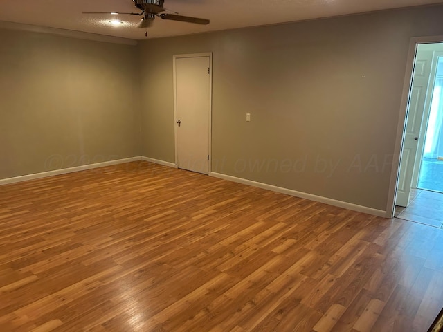empty room featuring baseboards, a ceiling fan, and wood finished floors