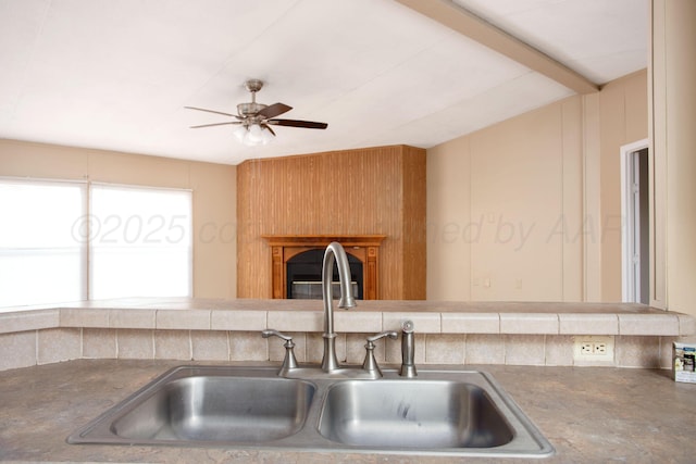 kitchen with a sink, ceiling fan, and a fireplace