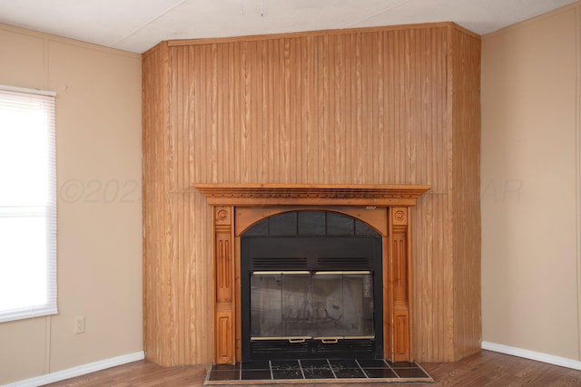 detailed view of a fireplace, wood finished floors, and baseboards