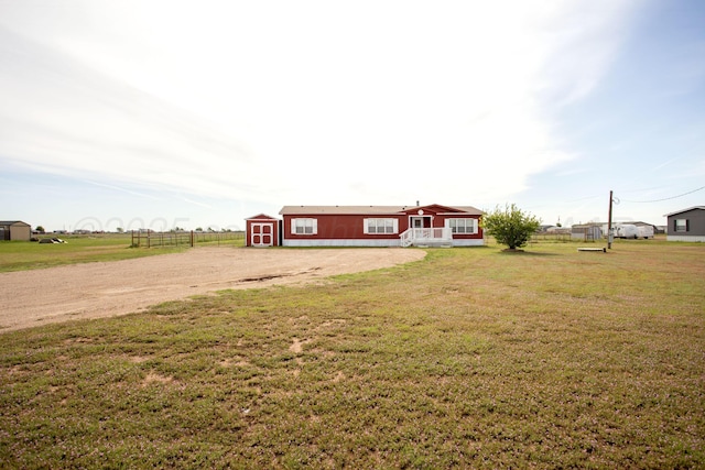 view of grassy yard featuring a storage shed, an outdoor structure, and dirt driveway