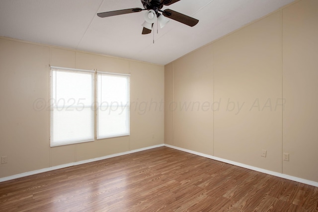 unfurnished room featuring lofted ceiling, wood finished floors, a ceiling fan, and baseboards