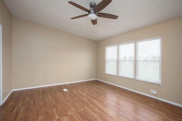 spare room with wood finished floors, lofted ceiling, a ceiling fan, and baseboards