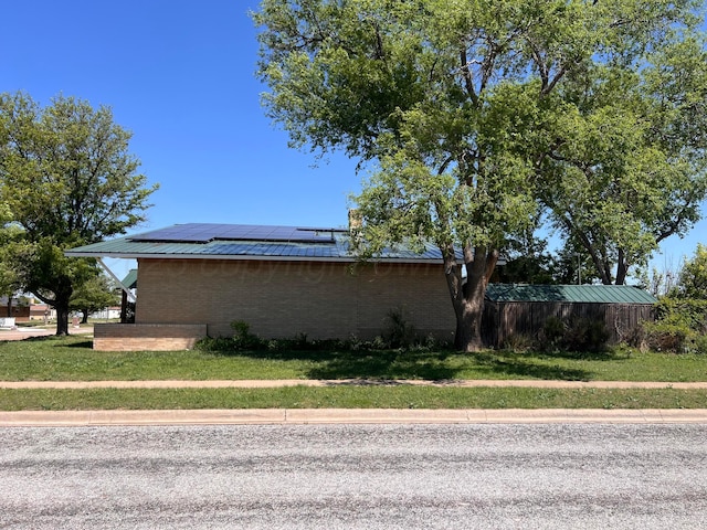 1400 16th St, Hereford, TX 79045 - view of property exterior with solar panels, brick siding, a yard, and metal roof