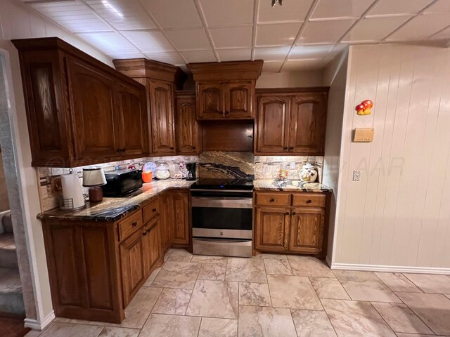 1400 16th St, Hereford, TX 79045 - kitchen with stainless steel electric range oven, decorative backsplash, baseboards, stone countertops, and wooden walls