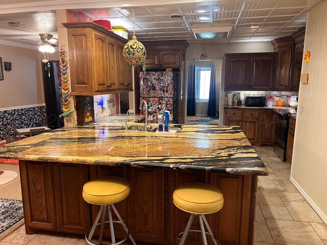 1400 16th St, Hereford, TX 79045 - kitchen featuring stainless steel range with electric stovetop, black microwave, a peninsula, and a breakfast bar