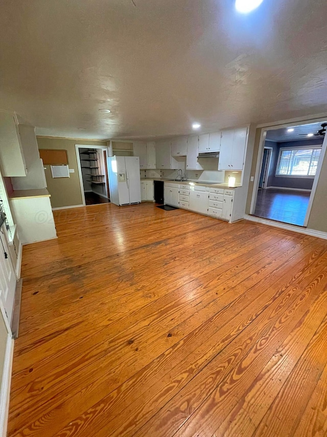 interior space with sink, white cabinets, white refrigerator with ice dispenser, and light wood-type flooring