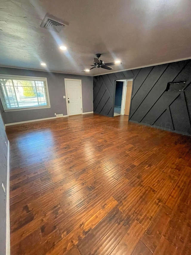 unfurnished living room featuring ceiling fan, hardwood / wood-style floors, and wooden walls