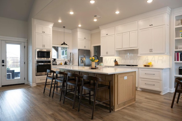kitchen featuring stainless steel appliances, white cabinetry, backsplash, a kitchen breakfast bar, and recessed lighting