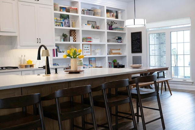 kitchen with open shelves, tasteful backsplash, white cabinets, a breakfast bar area, and decorative light fixtures