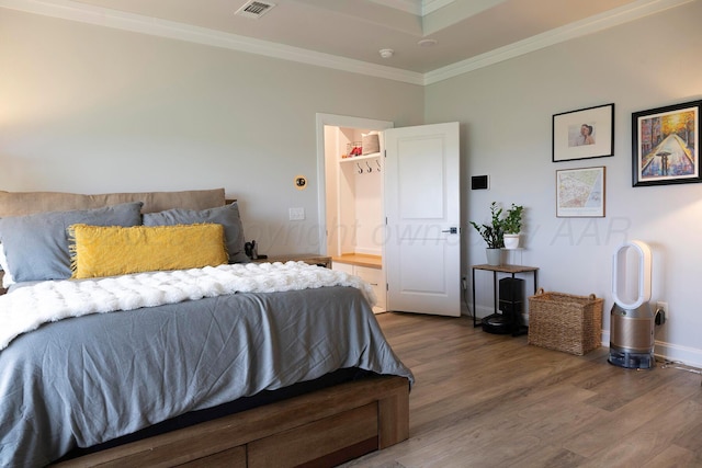 bedroom with wood finished floors, ornamental molding, and baseboards