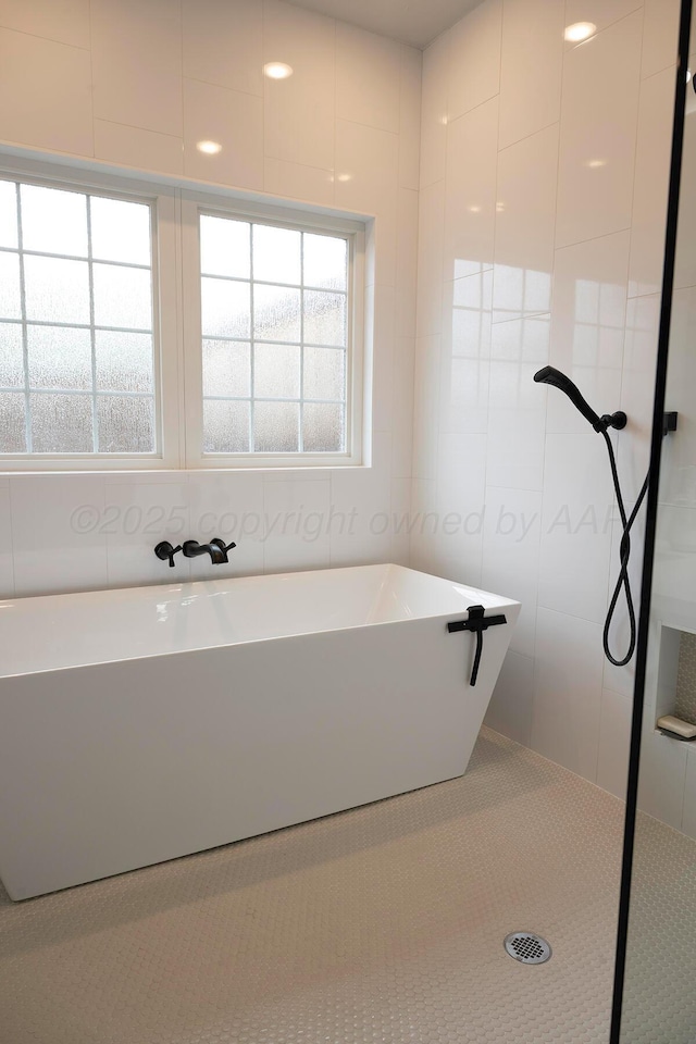 full bath with a freestanding tub, tiled shower, and tile walls