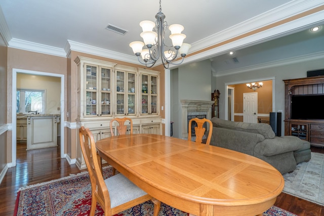 3501 Van Winkle Dr, Amarillo, TX 79121 - dining space featuring a chandelier, crown molding, dark wood-type flooring, and a fireplace