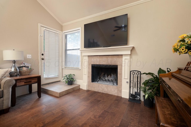 living room featuring crown molding, wood finished floors, a tile fireplace, a ceiling fan, and vaulted ceiling
