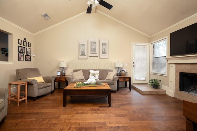 living room featuring ceiling fan, wood finished floors, lofted ceiling, a tile fireplace, and visible vents