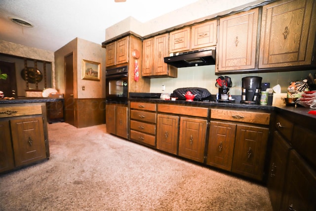 4204 Harmony St, Amarillo, TX 79109 - kitchen featuring under cabinet range hood, black oven, light colored carpet, and dark countertops