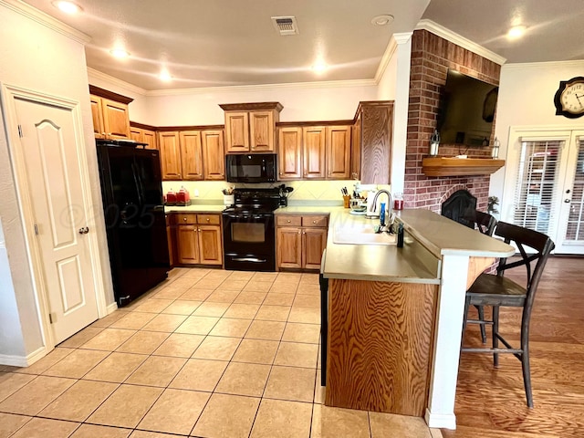 8400 El Paso Dr, Amarillo, TX 79118 - kitchen with a kitchen bar, a peninsula, visible vents, black appliances, and a sink