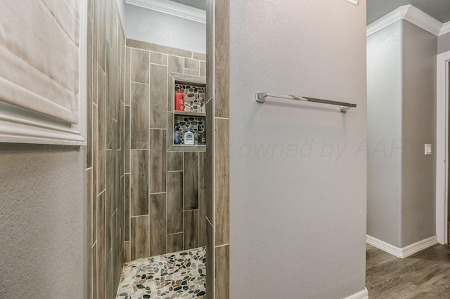 bathroom featuring tiled shower, wood-type flooring, and ornamental molding