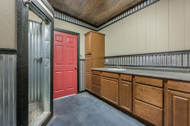 kitchen featuring wood walls, wooden ceiling, and sink