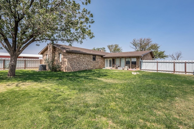 rear view of property with cooling unit and a lawn