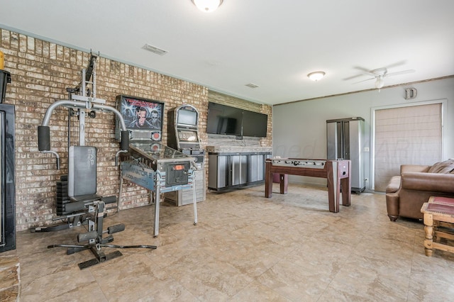 interior space with ceiling fan and brick wall