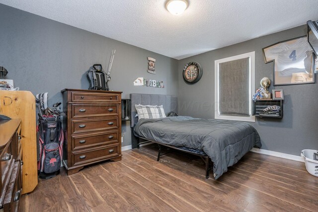 bedroom with a textured ceiling and dark hardwood / wood-style floors