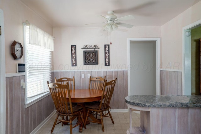 3406 Meadow Dr, Amarillo, TX 79109 - dining room featuring a ceiling fan, a wainscoted wall, light floors, and wood walls