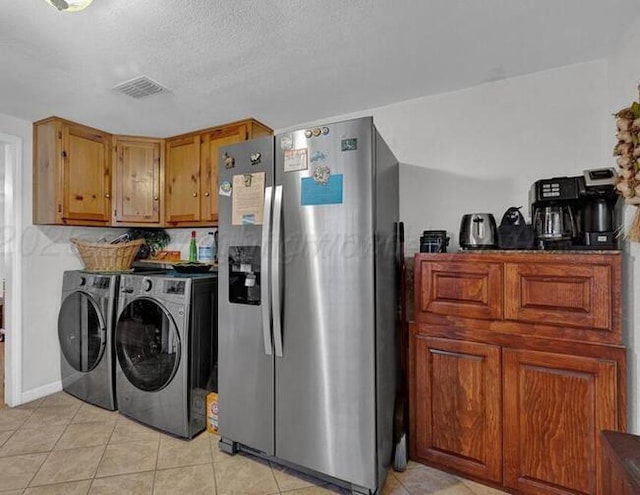 clothes washing area featuring washing machine and dryer, laundry area, visible vents, and light tile patterned floors