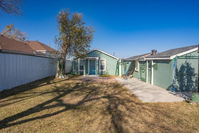 back of house with a yard, fence, and stucco siding