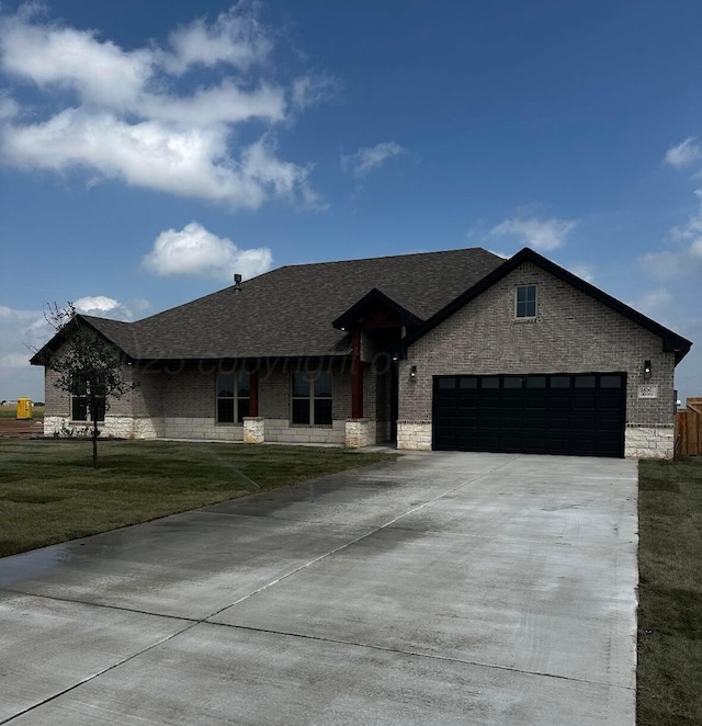 ranch-style home with a front lawn, a garage, brick siding, roof with shingles, and concrete driveway