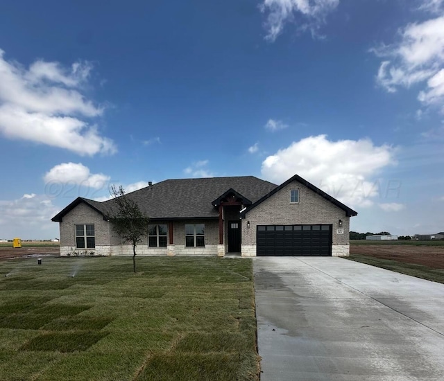 single story home featuring a front yard, stone siding, a garage, and concrete driveway