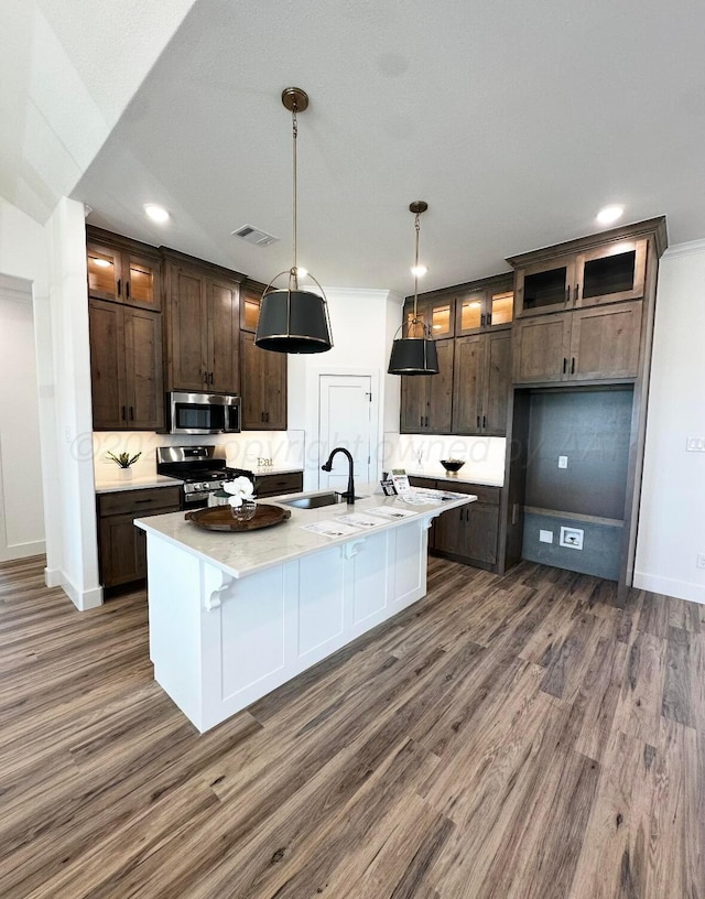 kitchen featuring stainless steel appliances, dark brown cabinets, dark wood-type flooring, and a sink