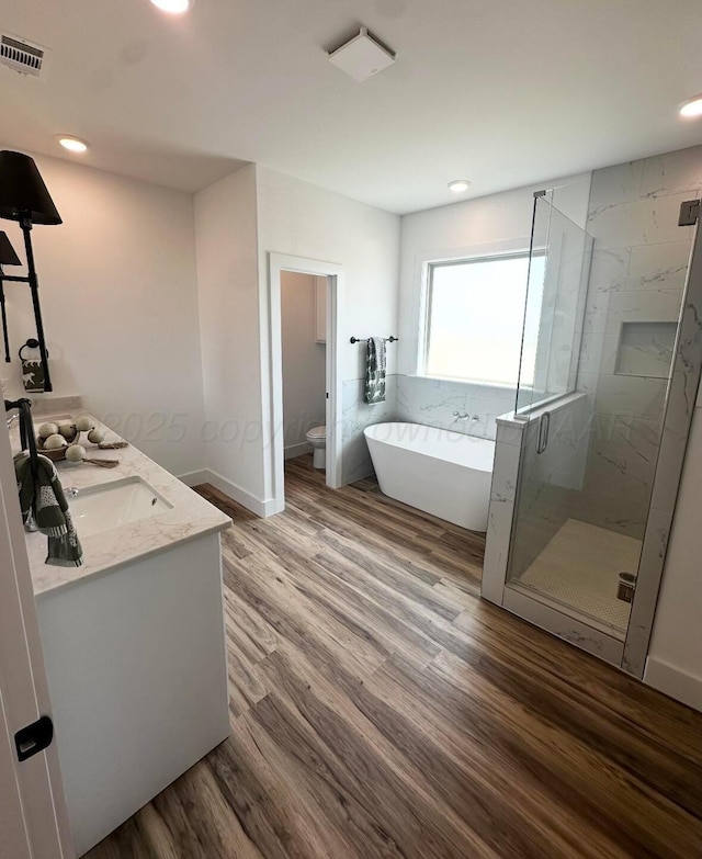 full bathroom with toilet, a marble finish shower, visible vents, a soaking tub, and wood finished floors