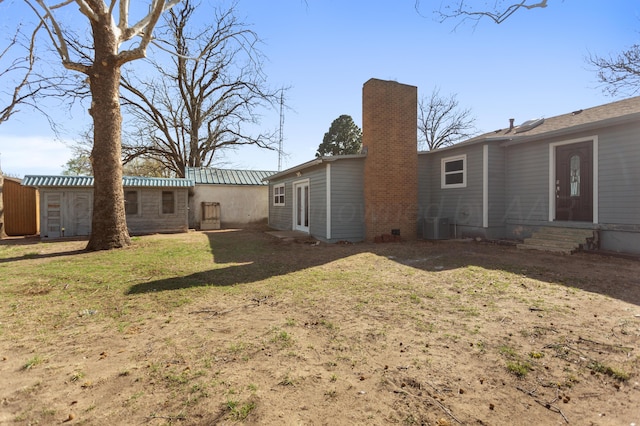 rear view of house with a lawn, a chimney, and entry steps