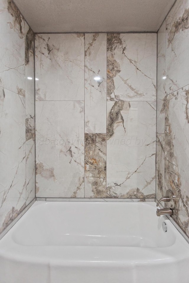full bath with a textured ceiling and washtub / shower combination