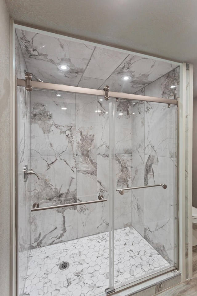 bathroom featuring toilet and a marble finish shower