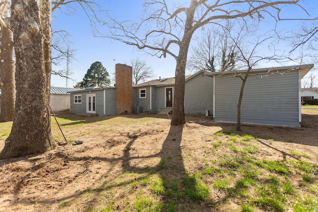 back of property with central AC unit and a chimney