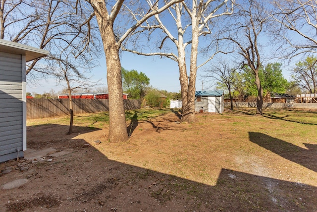 view of yard with an outbuilding, fence, and a storage shed