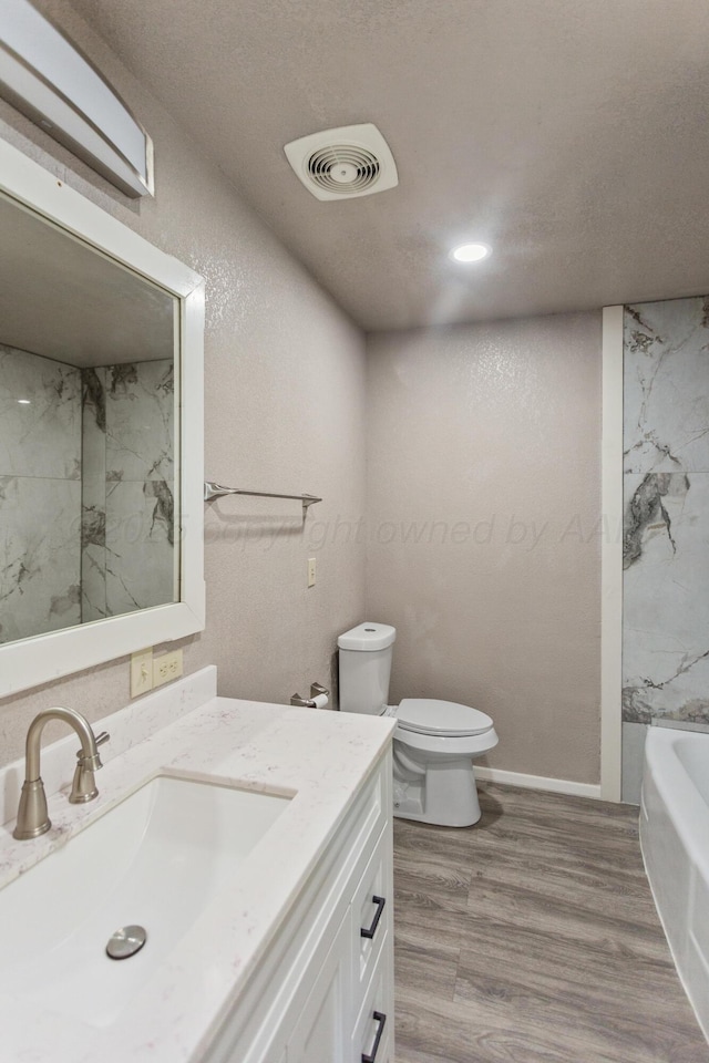 full bathroom with vanity, a bathing tub, toilet, visible vents, and wood finished floors
