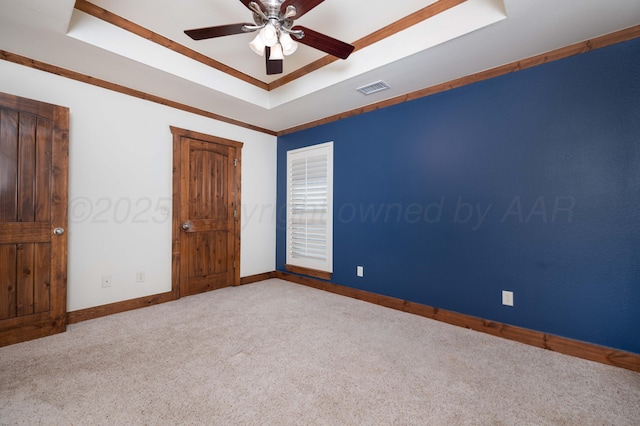 carpeted spare room featuring visible vents, a ceiling fan, a raised ceiling, and baseboards