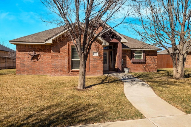 ranch-style house featuring a front lawn, fence, brick siding, and a shingled roof