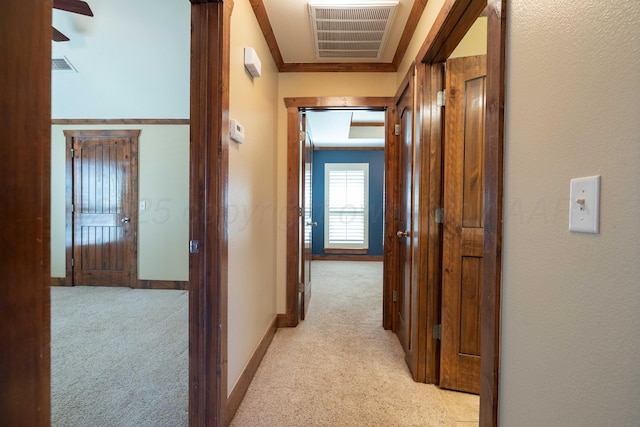 hall featuring light carpet, visible vents, baseboards, and ornamental molding