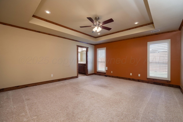 unfurnished room featuring a tray ceiling, visible vents, and light carpet