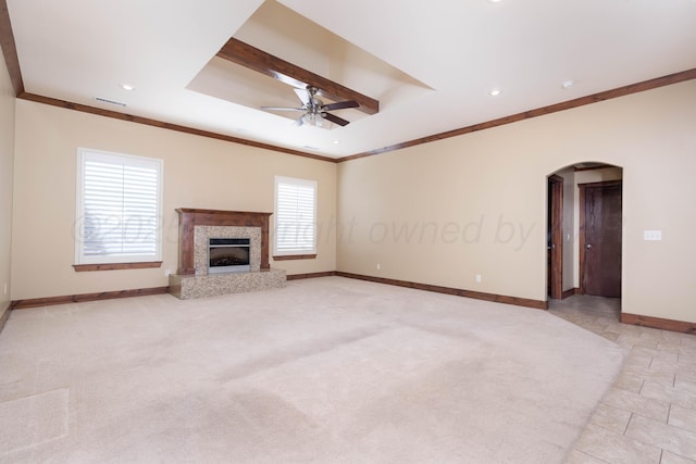 unfurnished living room with baseboards, a premium fireplace, arched walkways, ceiling fan, and light carpet