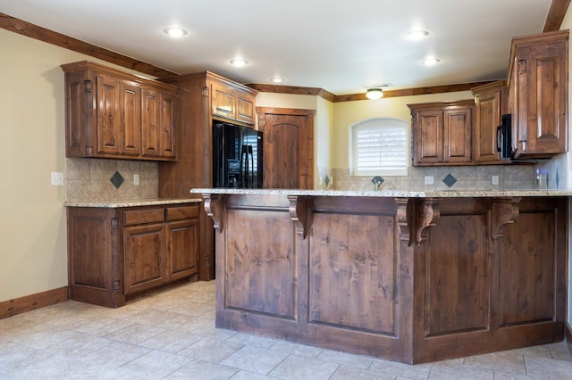 kitchen featuring baseboards, light stone countertops, a breakfast bar area, decorative backsplash, and black appliances