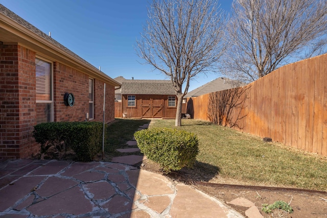 view of yard with an outbuilding, a shed, a patio, and a fenced backyard