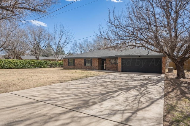 view of front of home featuring driveway, brick siding, an attached garage, and a front yard